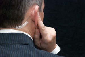 25307685 - close-up of a secret service agent listening to his earpiece, over the shoulder.